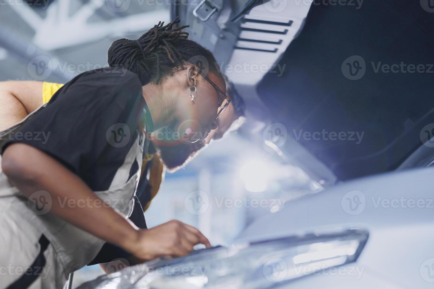 Trained engineers using oil extractor tool to change old car transmission fluid with new one in repair shop. Garage workspace specialists using professional equipment to do vehicle maintenance photo