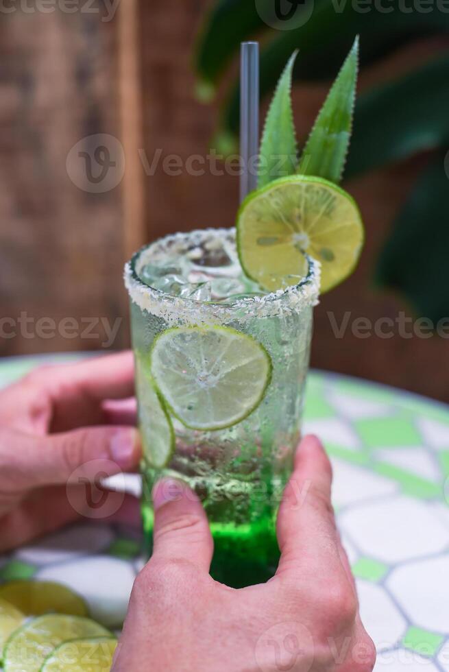 Hands holding panda leaves lemonade with desiccated coconut and green syrup on natural leaves background with copy space photo