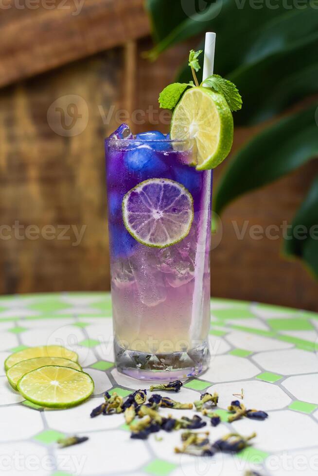 Lemonade with butterfly pea flowers and blue syrup on wooden background with copy space photo