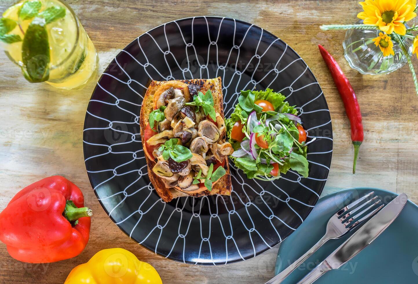 Mushrooms on the toast with hummus, garlic butter, thyme and truffle oil on wooden table with fork, knife and lemonade drink photo