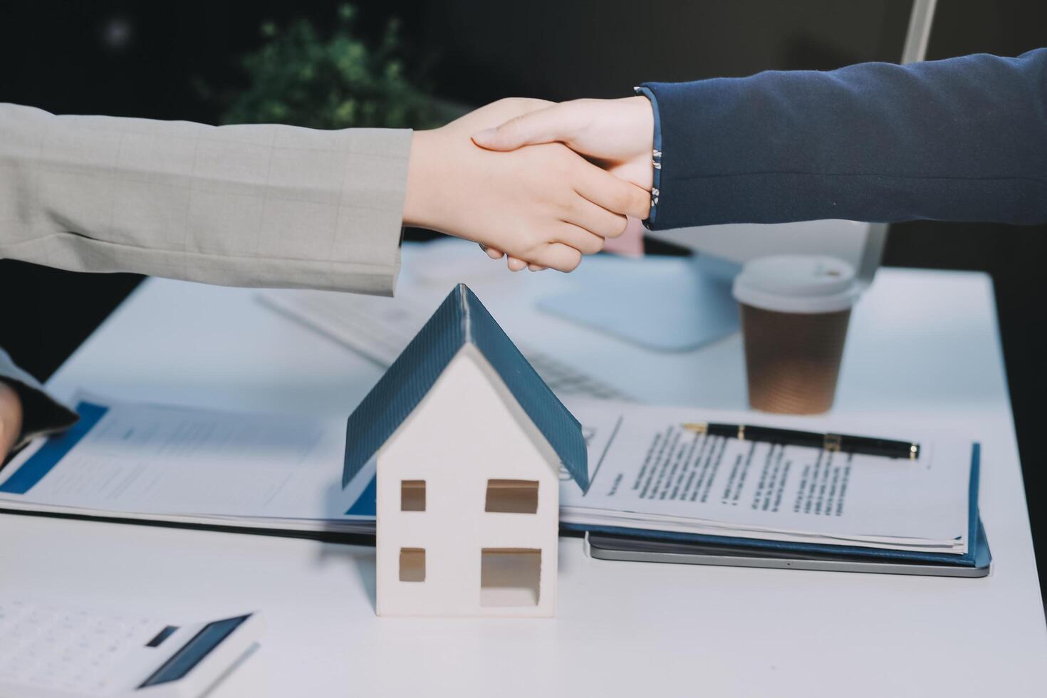 Two people shaking hands over a house model photo
