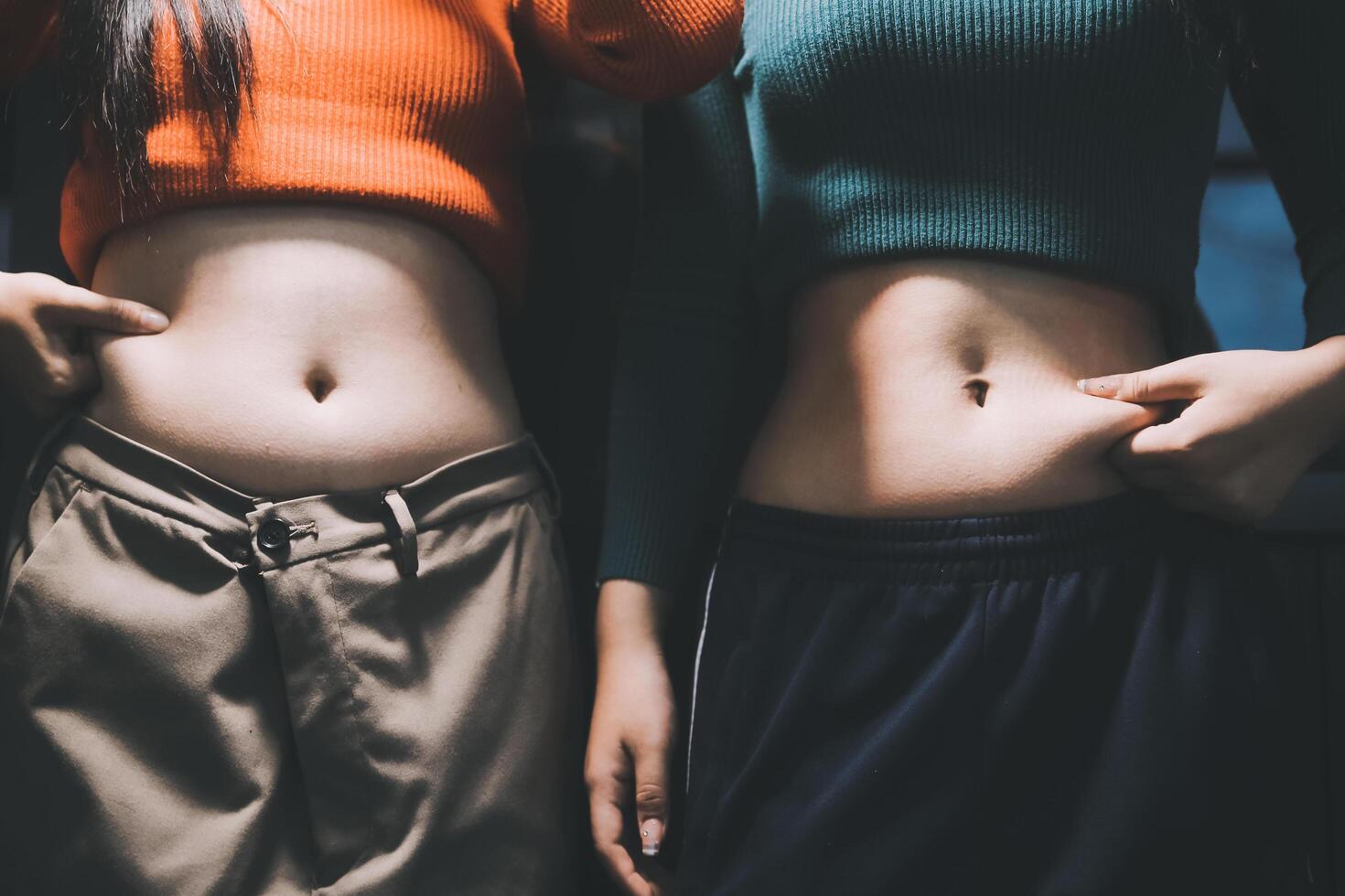 Two women with their stomachs showing photo