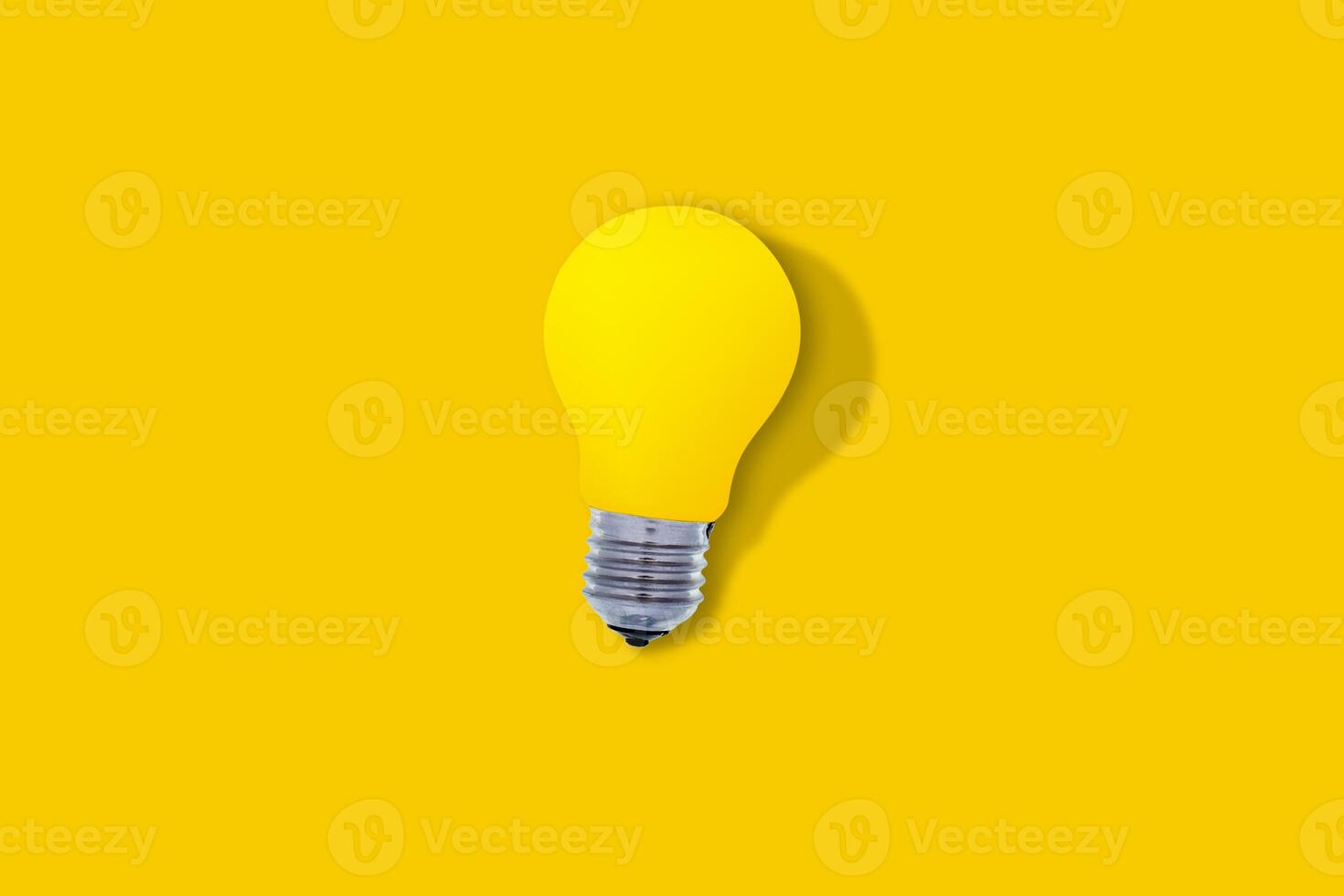 Yellow glass bulb with hard shadow, on yellow background, with copy space. Ideas and lighting concept photo