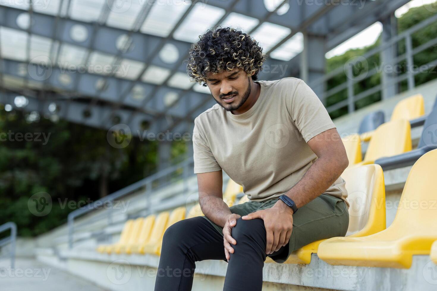 A man injured his leg while doing active physical exercises and fitness, a sportsman massages his knee muscle while sitting. photo