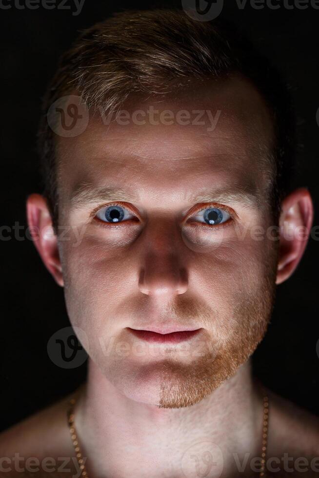 Young man shaving his beard. He shaved off half the bristles against a gray background. Male face care. Shaving bristles. The difference between skin without hair and with a mustache photo