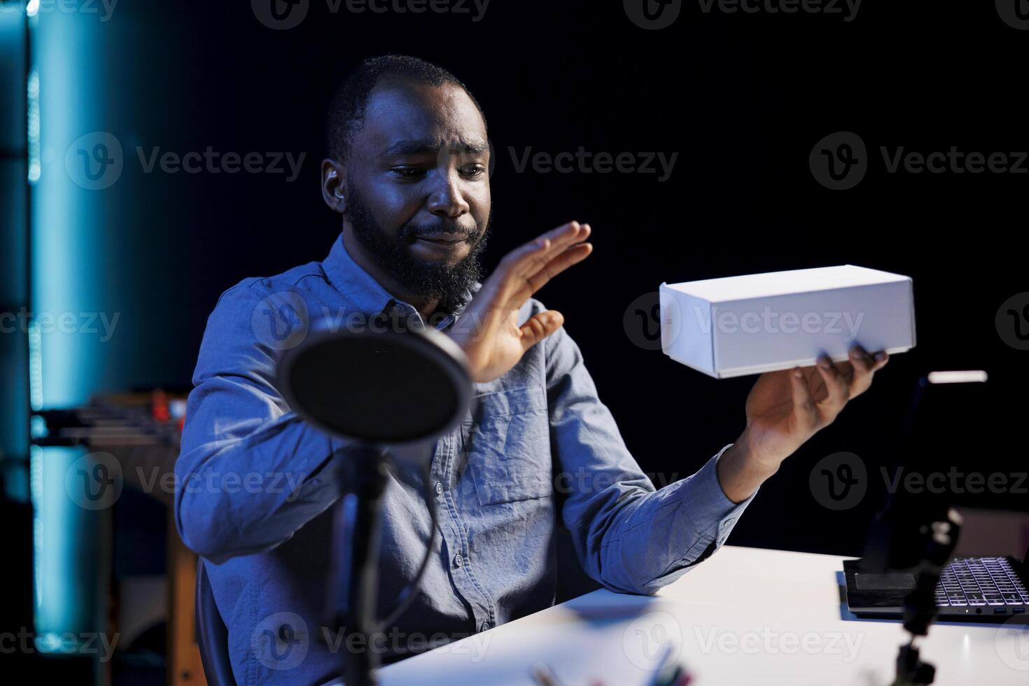 Smiling content creator at home holding product box in hand, preparing to unbox in after finishing introduction. Trending influencer doing tech item review for viewers photo