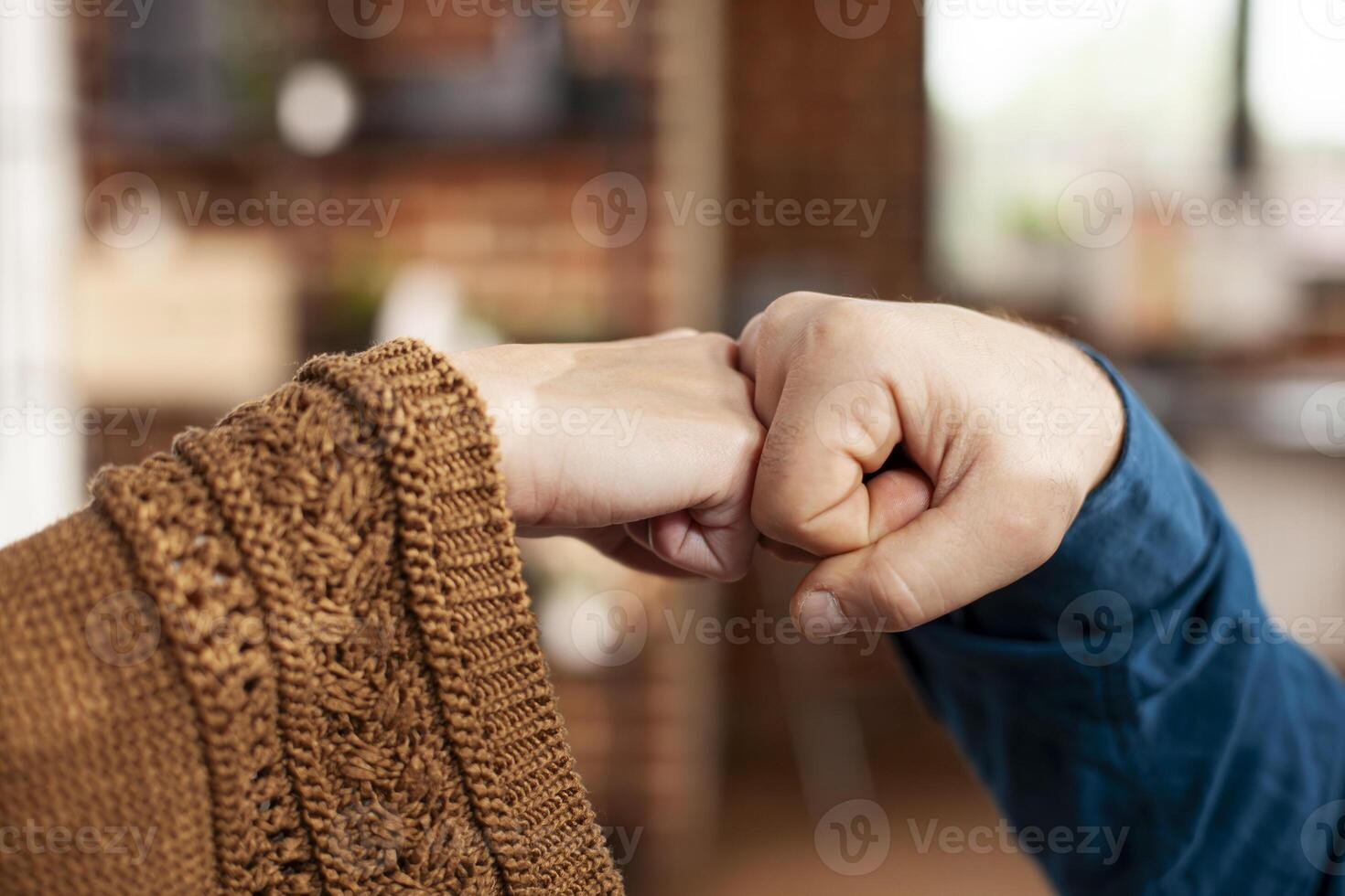 Closeup of colleagues doing hand gestures, representing unity and success. Businessman and woman exchange fist bump greetings, ensuring safe pandemic guidelines in startup office. photo