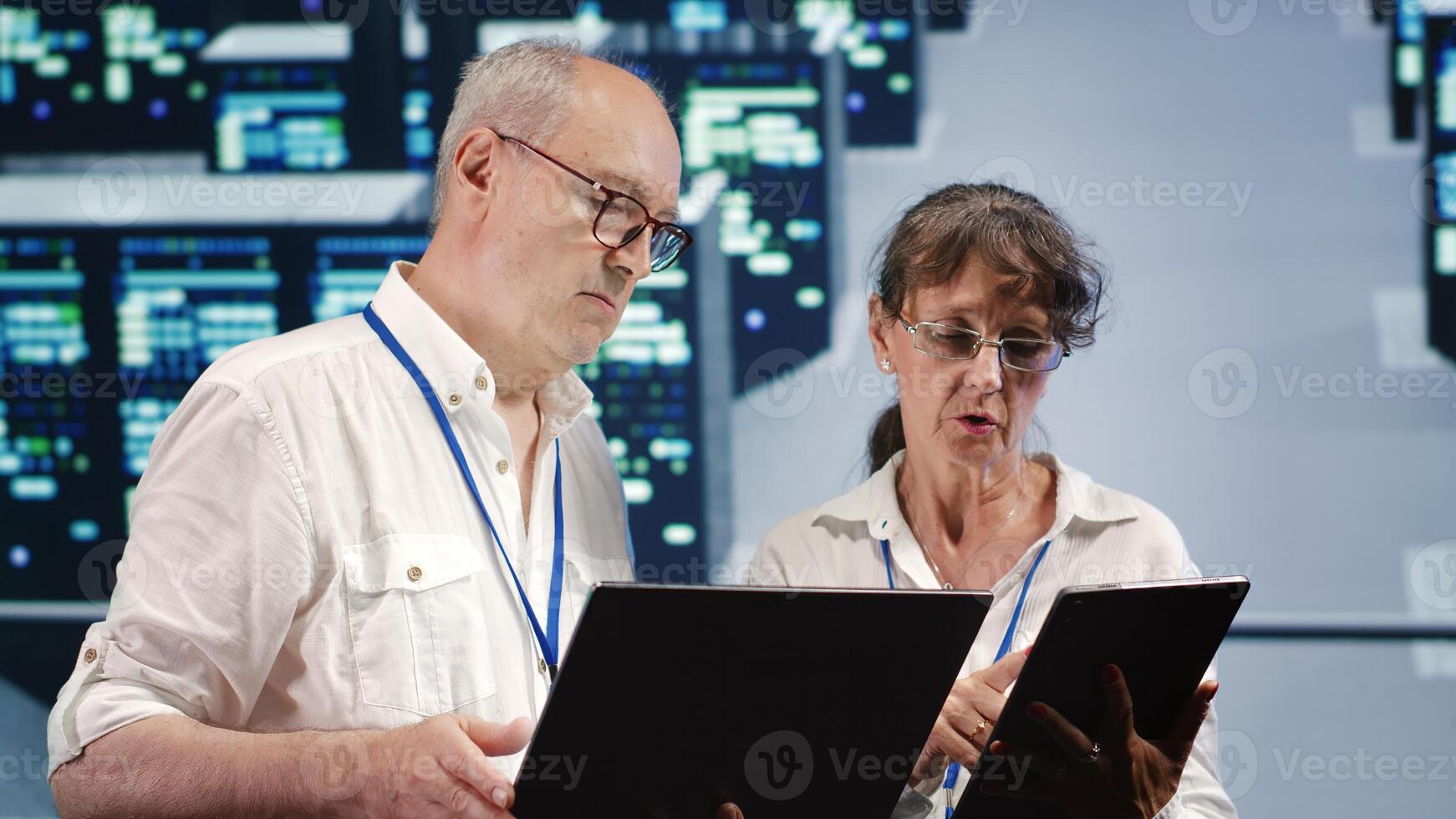 Data storage company executives looking around data center, using laptop and tablet to crosscheck contingency plan and assess high tech workspace units in need of fixing, preventing liabilities photo