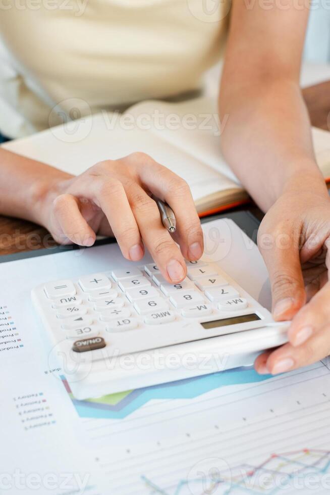 Hands using a calculator on financial documents with graphs, ideal for business, finance, and accounting themes. photo