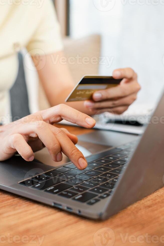 Hands holding a credit card and typing on a laptop, illustrating online shopping or e-commerce in a comfortable setting. photo