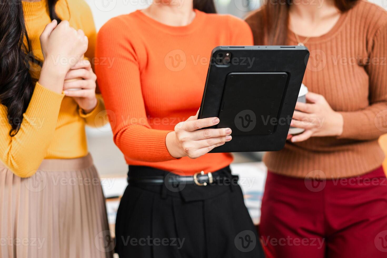 Three women using a tablet for collaboration in a modern office environment, showcasing teamwork and technology. photo