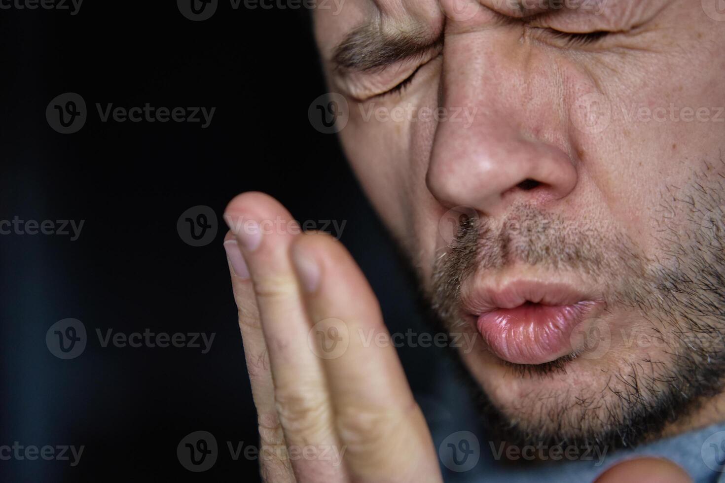 Bad breath from mouth. Man checking his breath by exhaling in his hand photo