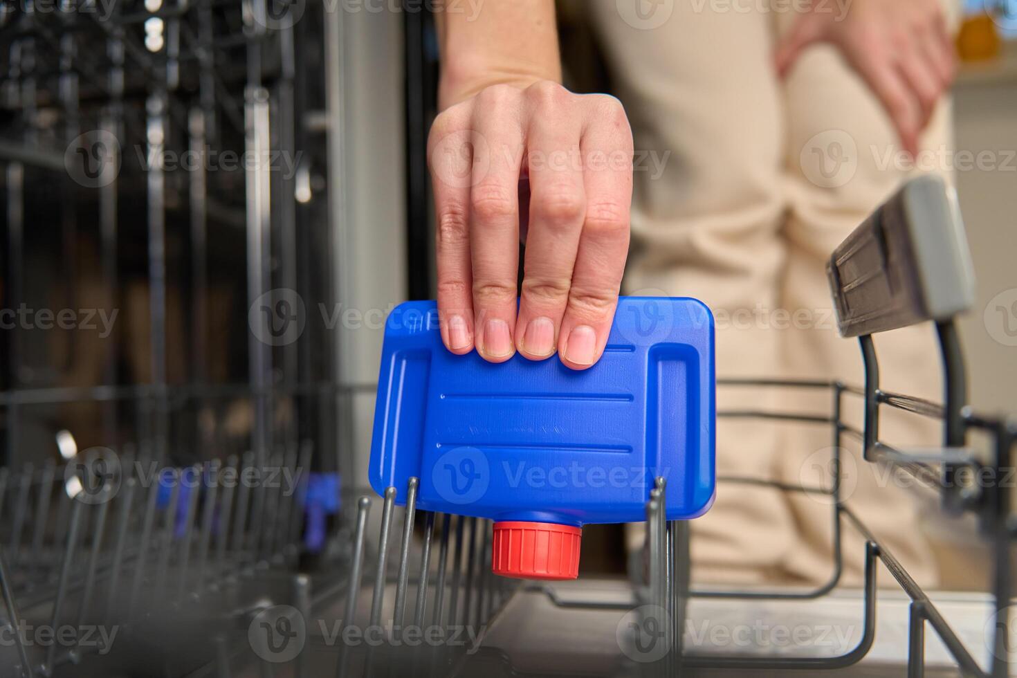 Hand placing dishwasher cleaner bottle inside dishwasher photo