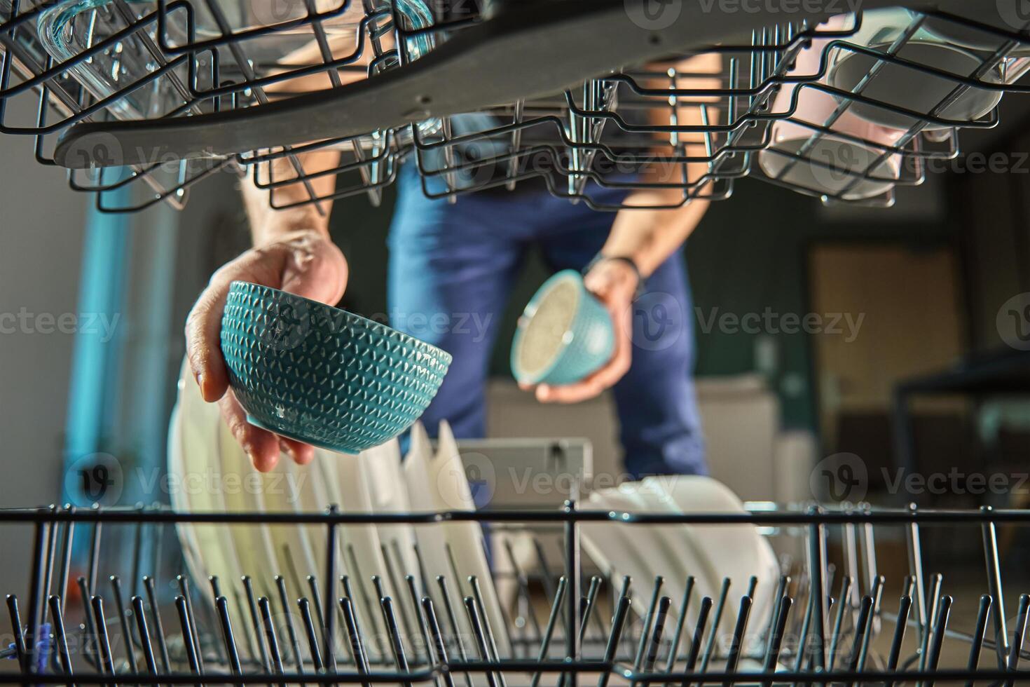 Man loading plates into dishwasher in kitchen photo