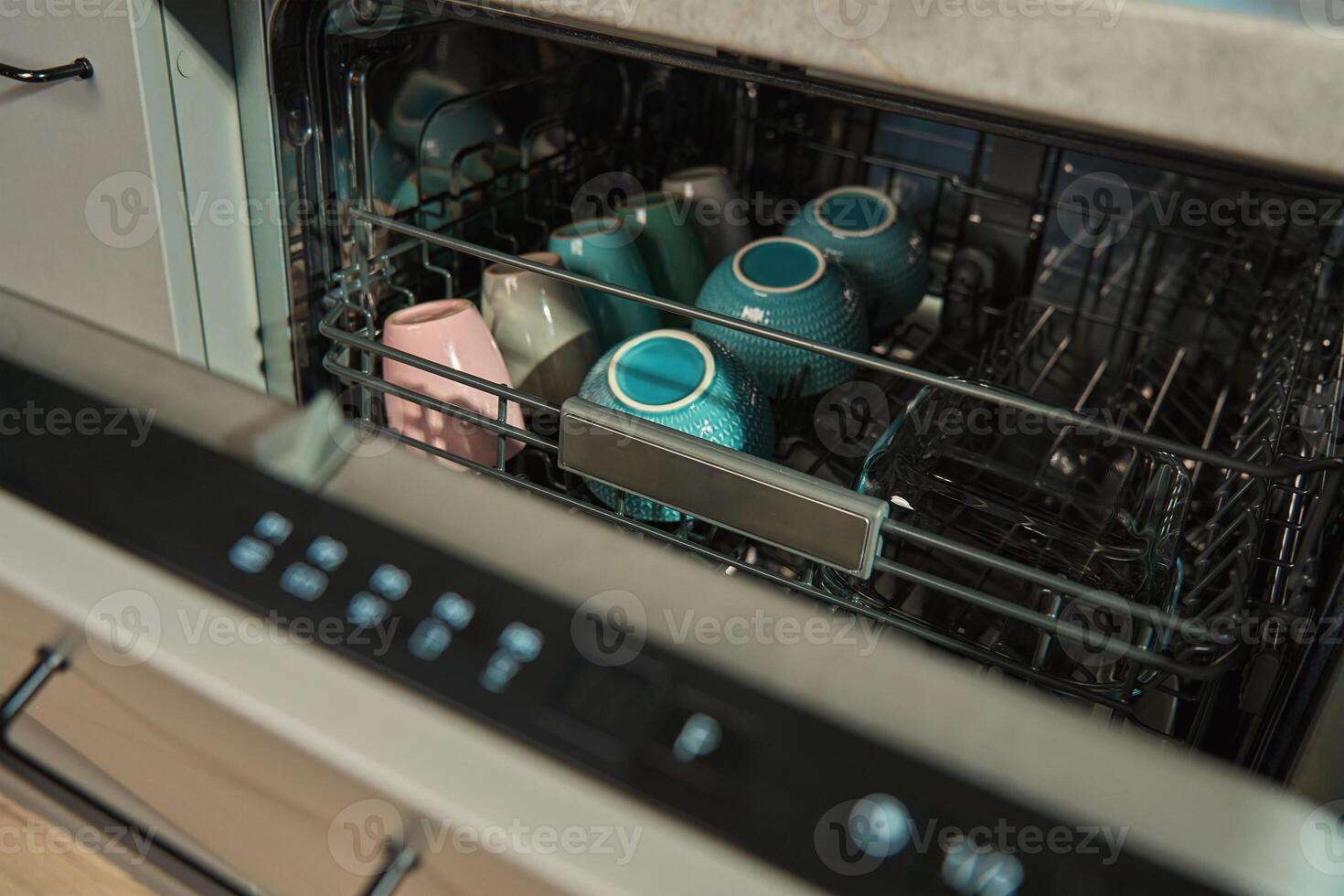 Dishwasher loaded with ceramic cups and bowls photo