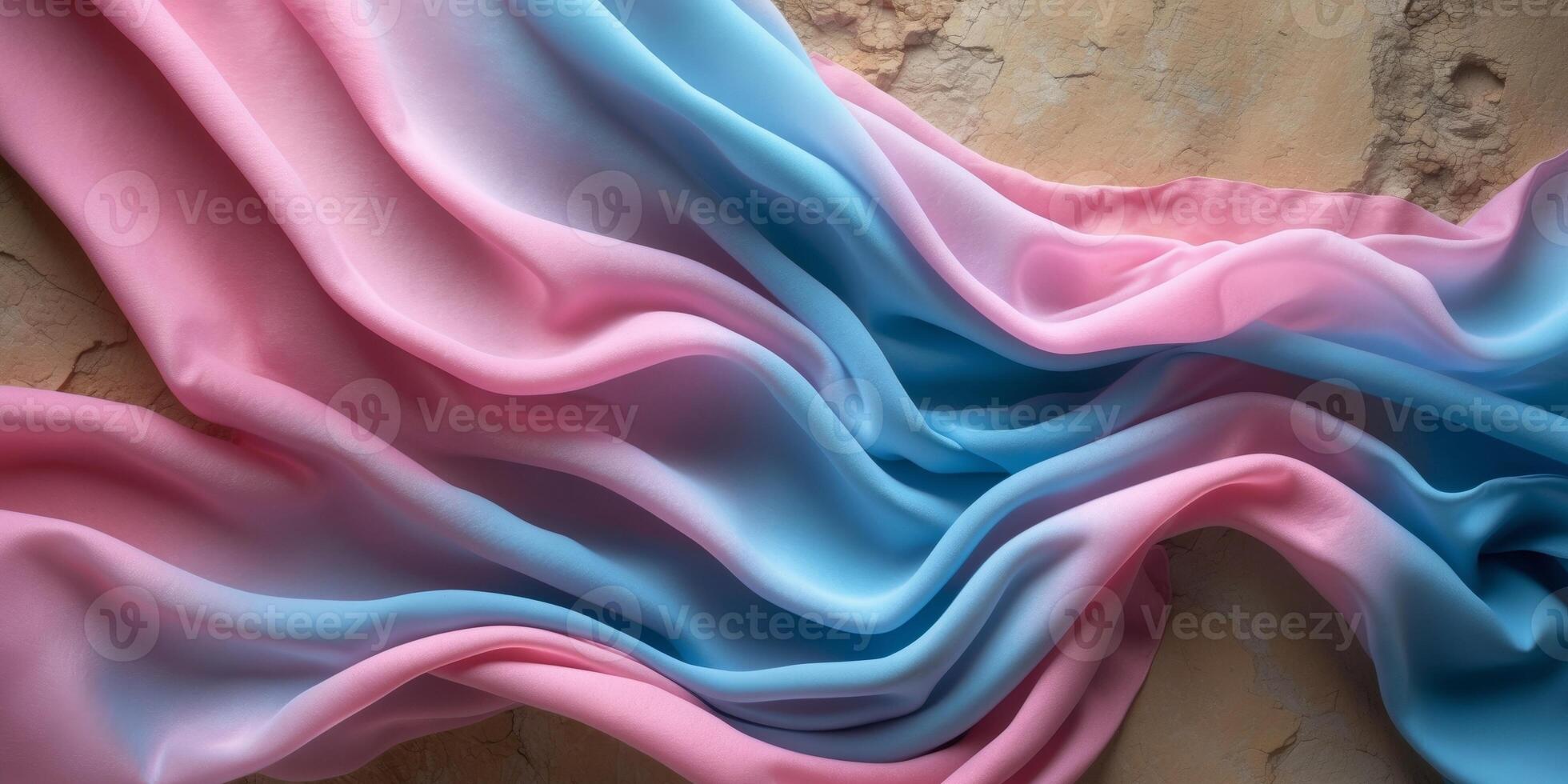 Flowing pink and blue fabric creating a gradient effect on textured background. photo