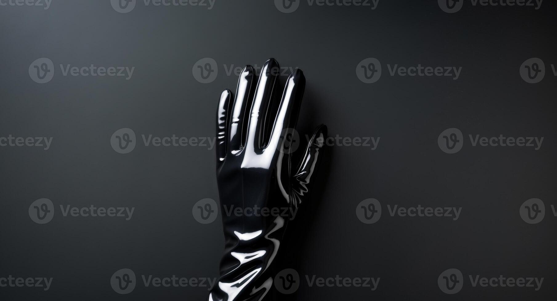 Shiny black latex gloves touching black latex background. photo