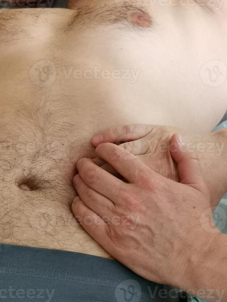 A real osteopath work with a man's abdomen. . Visceral massage to remove clamps and tension from the sphincters in the gastrointestinal tract. Visceral osteopathy photo