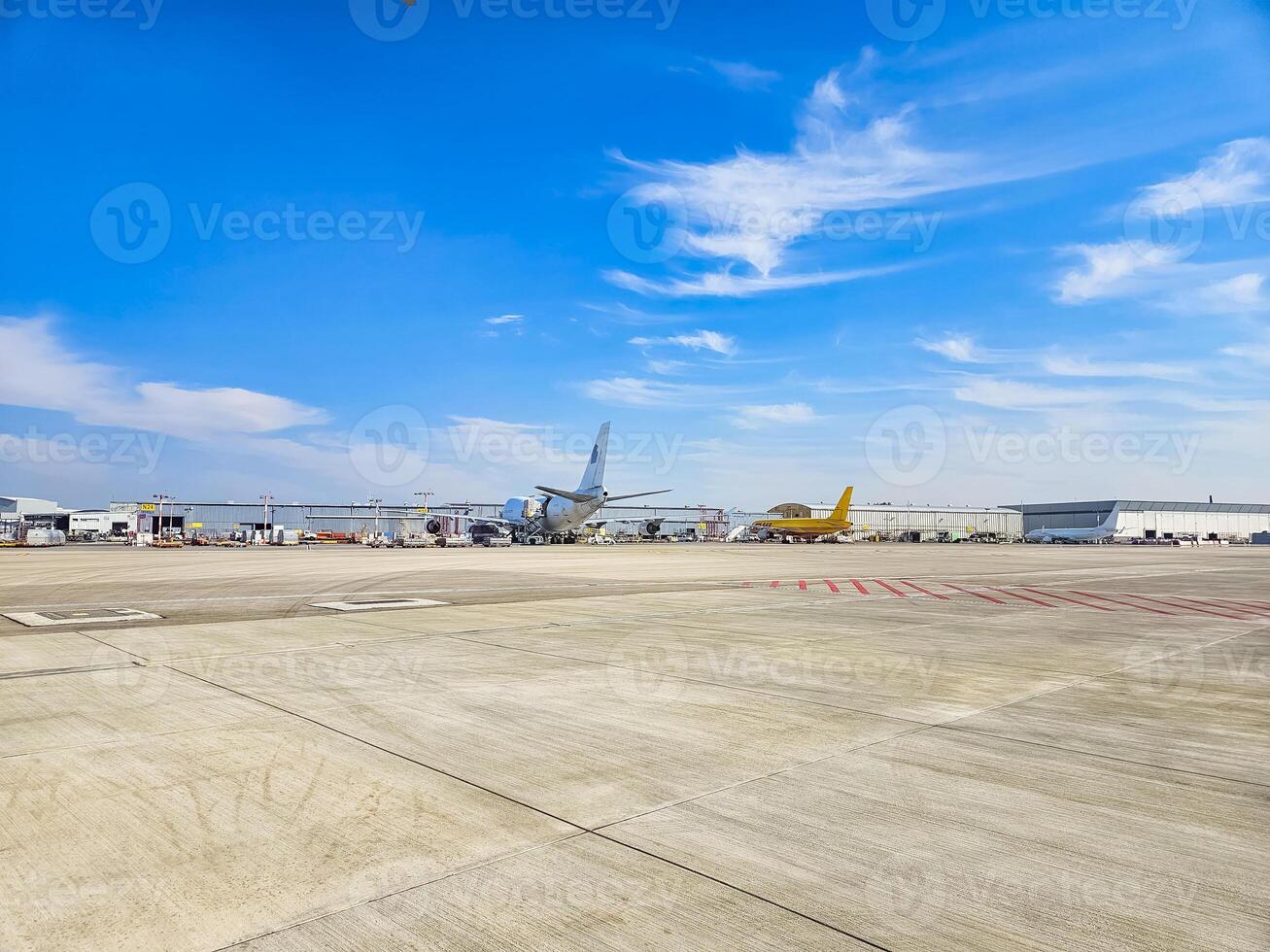 Airport tarmac with parked planes under a blue sky with scattered clouds. High quality photo