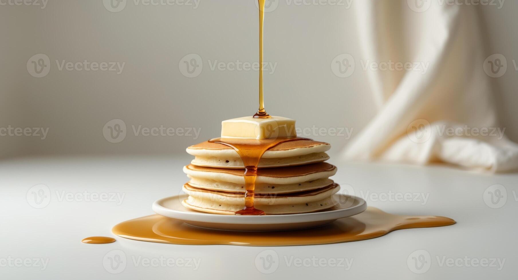 A stack of fluffy pancakes topped with butter and syrup drizzling down photo