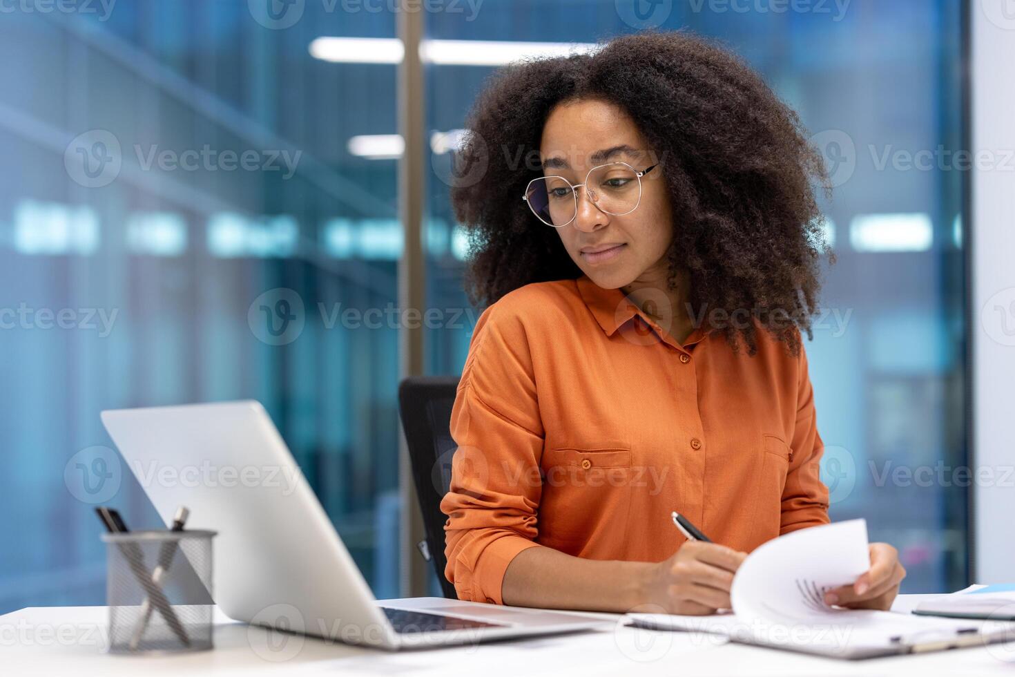 Serious focused woman doing paperwork inside office. Accountant financier signing contracts and filling out tax forms. Businesswoman with documents and graphs reports. photo