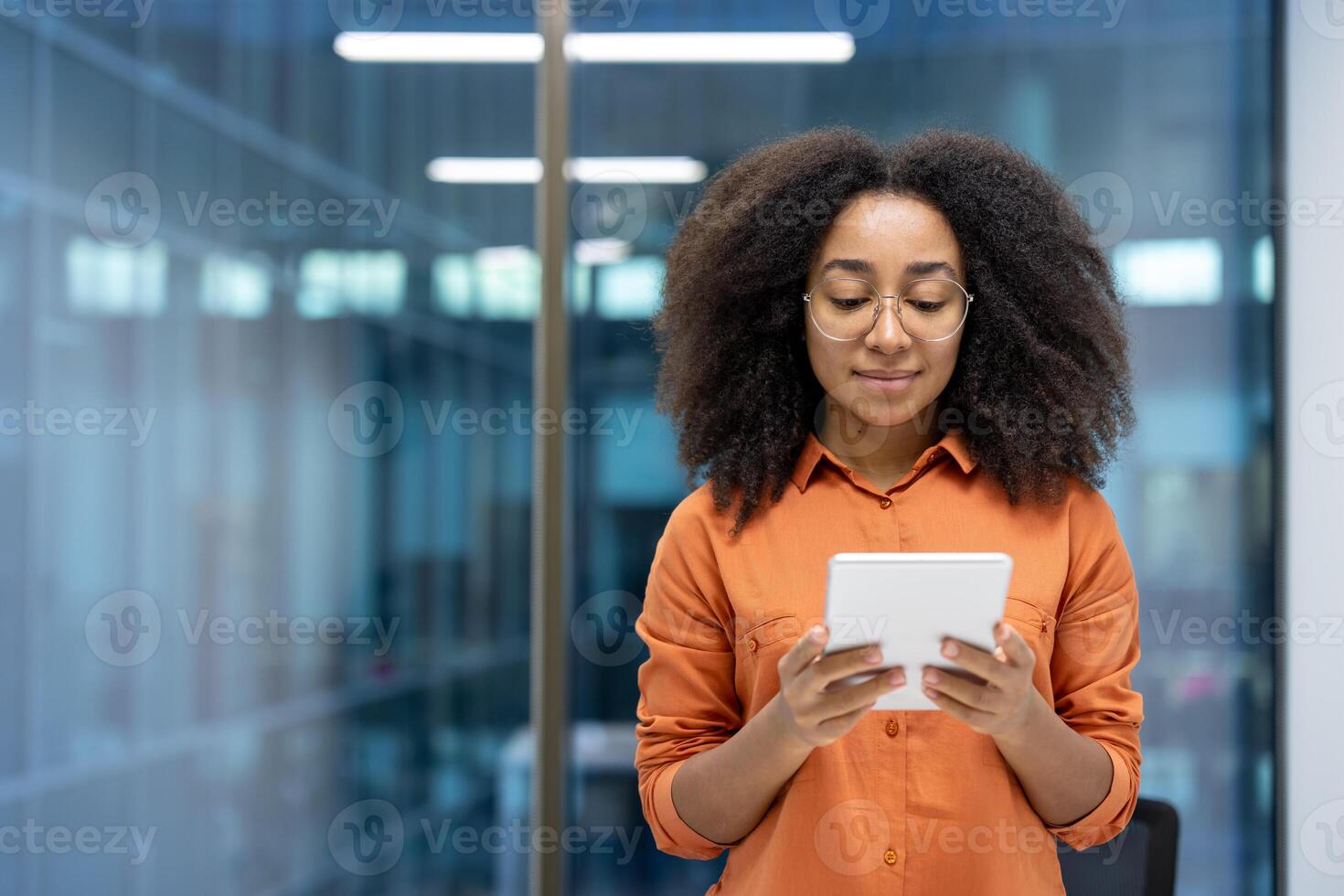 Serious woman with tablet computer standing near window, businesswoman thinking using online application. Office worker inside office, reading electronic financial report. photo