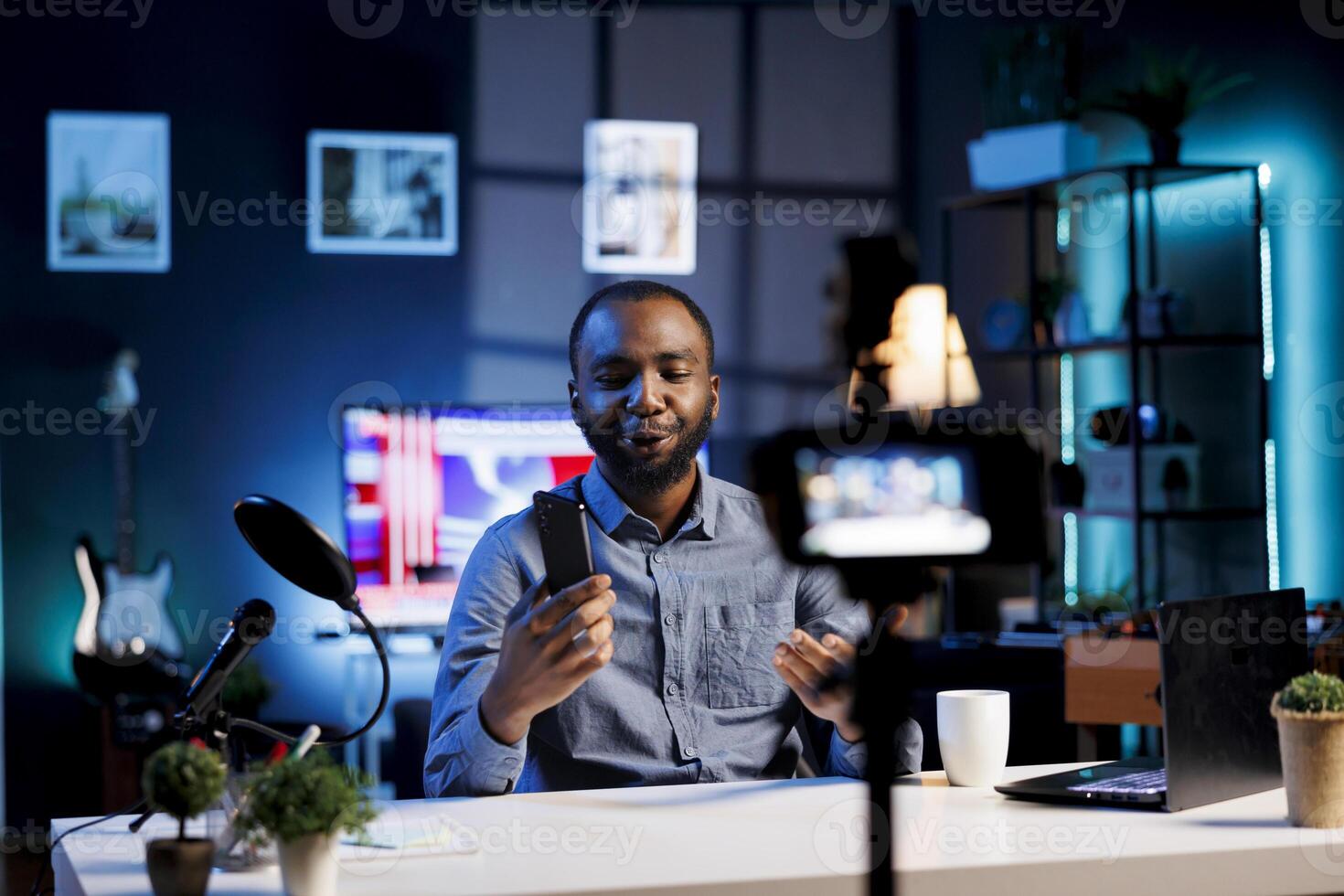 Entertainer at home holding newly launched smartphone in hand, preparing to present specs after finishing introduction. Influencer doing cellphone review for viewers, convincing them to buy it photo