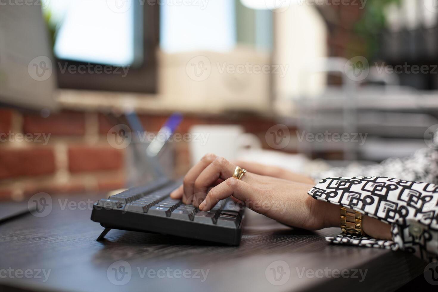 Female professional typing and inputting data, making updates to the company' project plan in modern workspace. Closeup view of an individual using office keyboard on a desk. photo