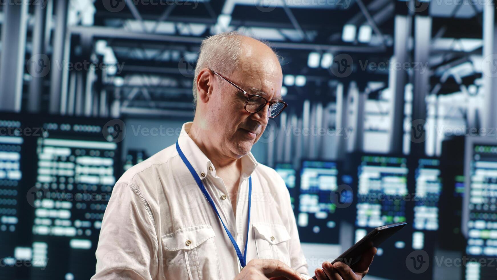 Aged professional navigating network of server rigs in industrial headquarters. IT programmer with tablet doing examination and optimizations in high tech data center, preventing system concerns photo
