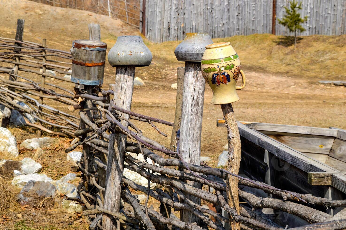 Old clay and cast-iron pots hanging on the fence. Old Slavic style. Ancient way of drying dishes photo