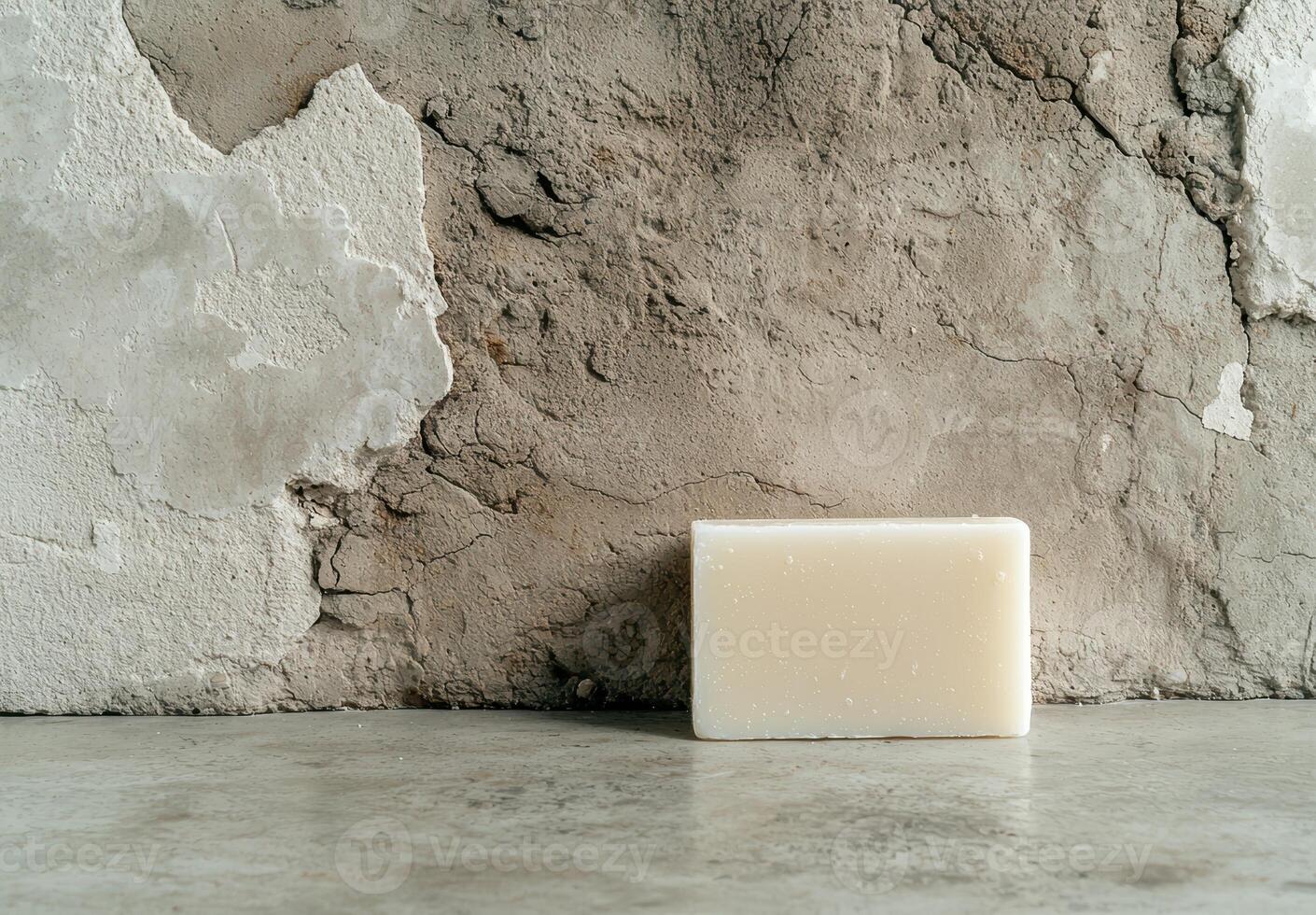 A bar of soap sits on a rustic surface against a textured wall photo