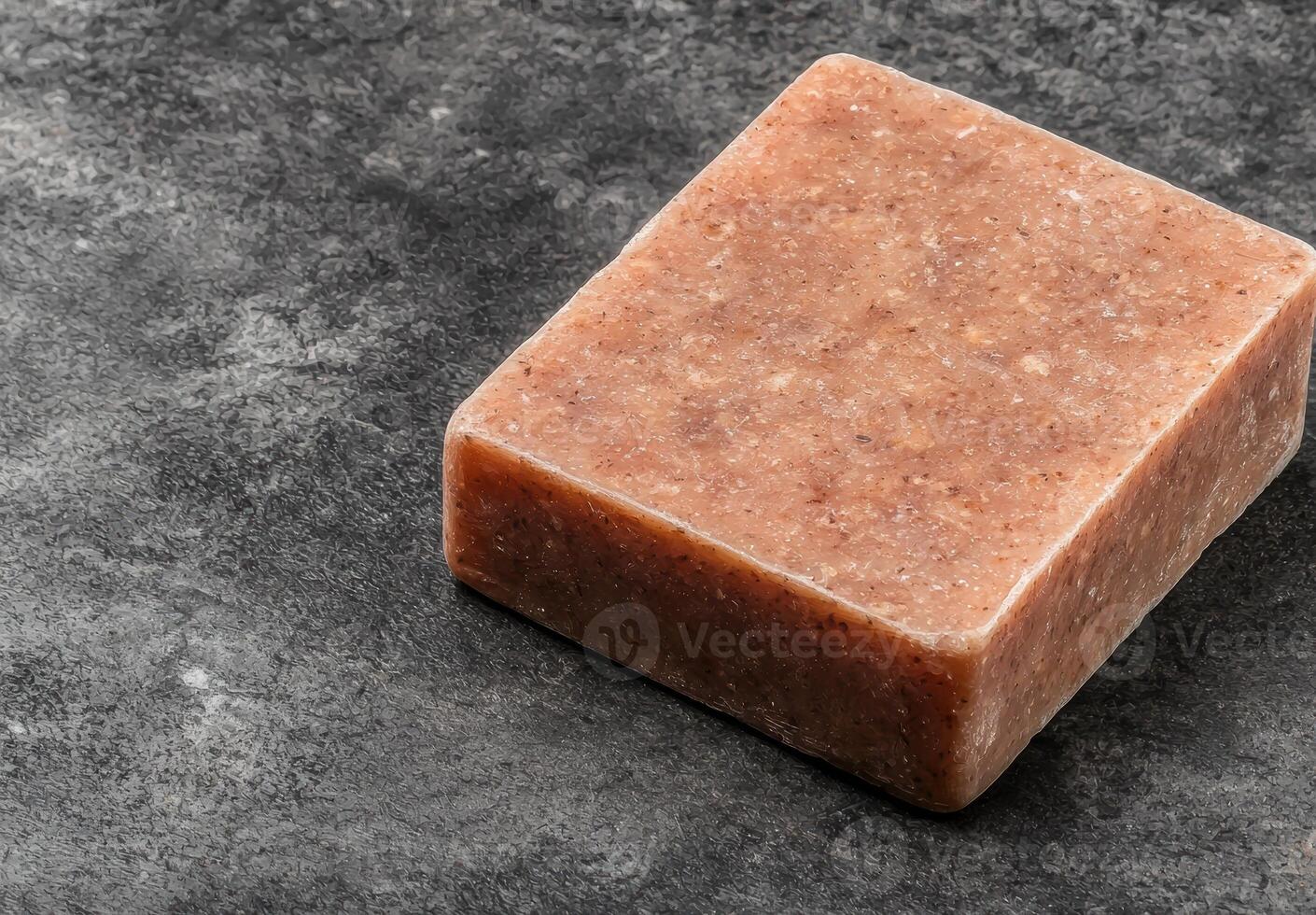 A square bar of exfoliating soap sits on a dark gray surface photo