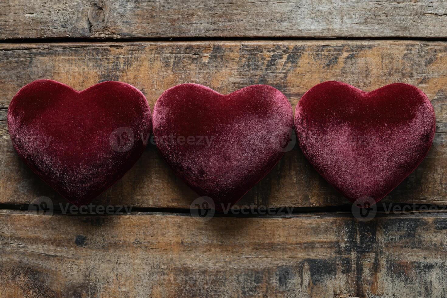 Three velvet hearts representing love and affection on rustic wooden background photo