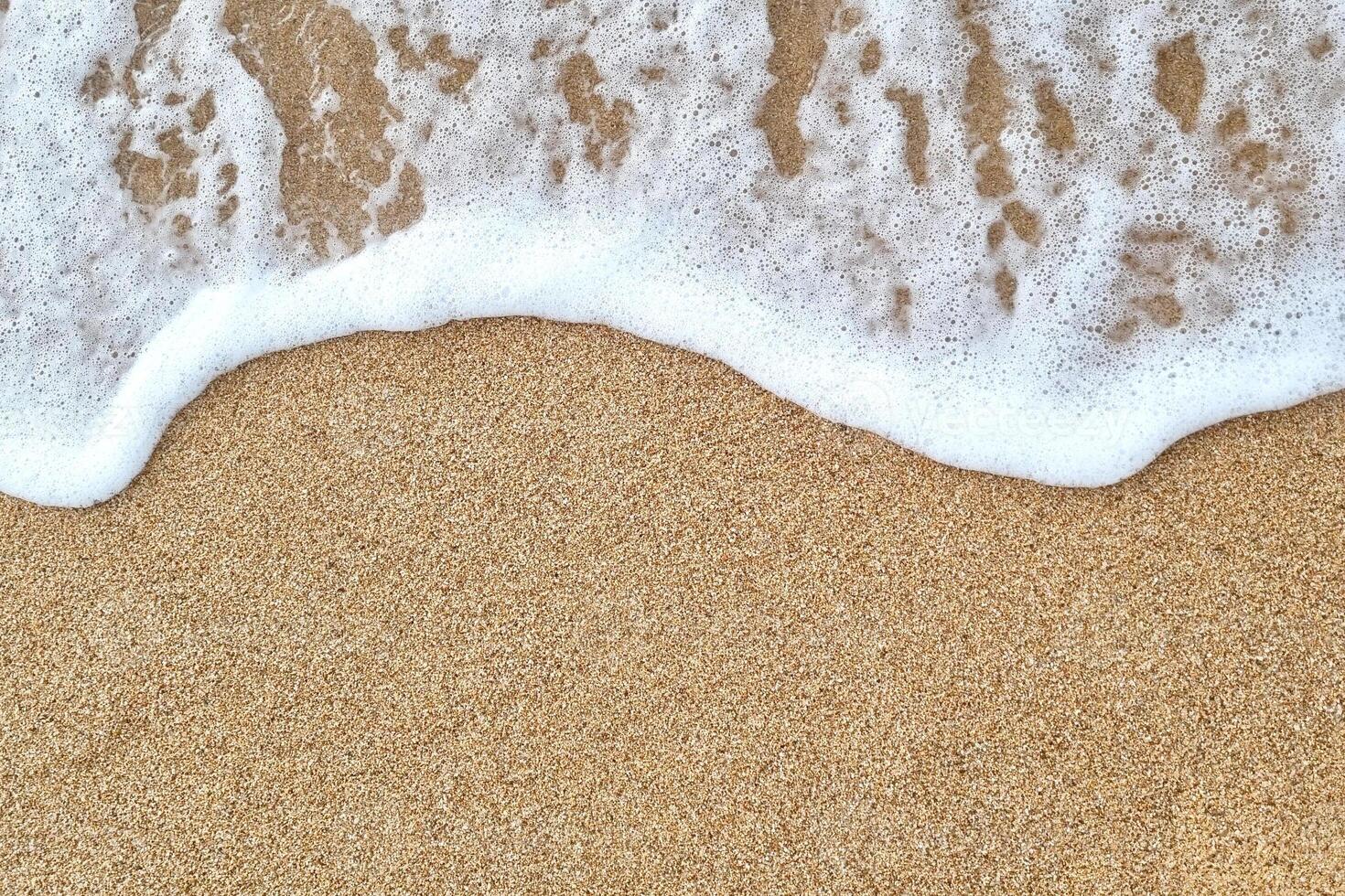 A wave on the sand with white foam photo