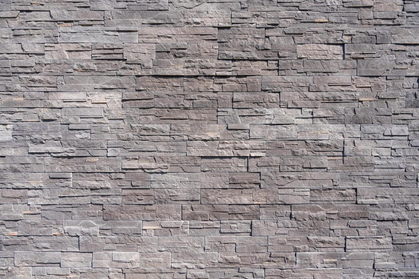 A detailed view of a modern gray stone wall with rectangular patterns and rough texture. photo