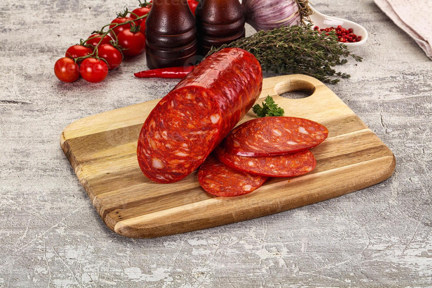 A wooden cutting board with a sliced up sausage on it photo