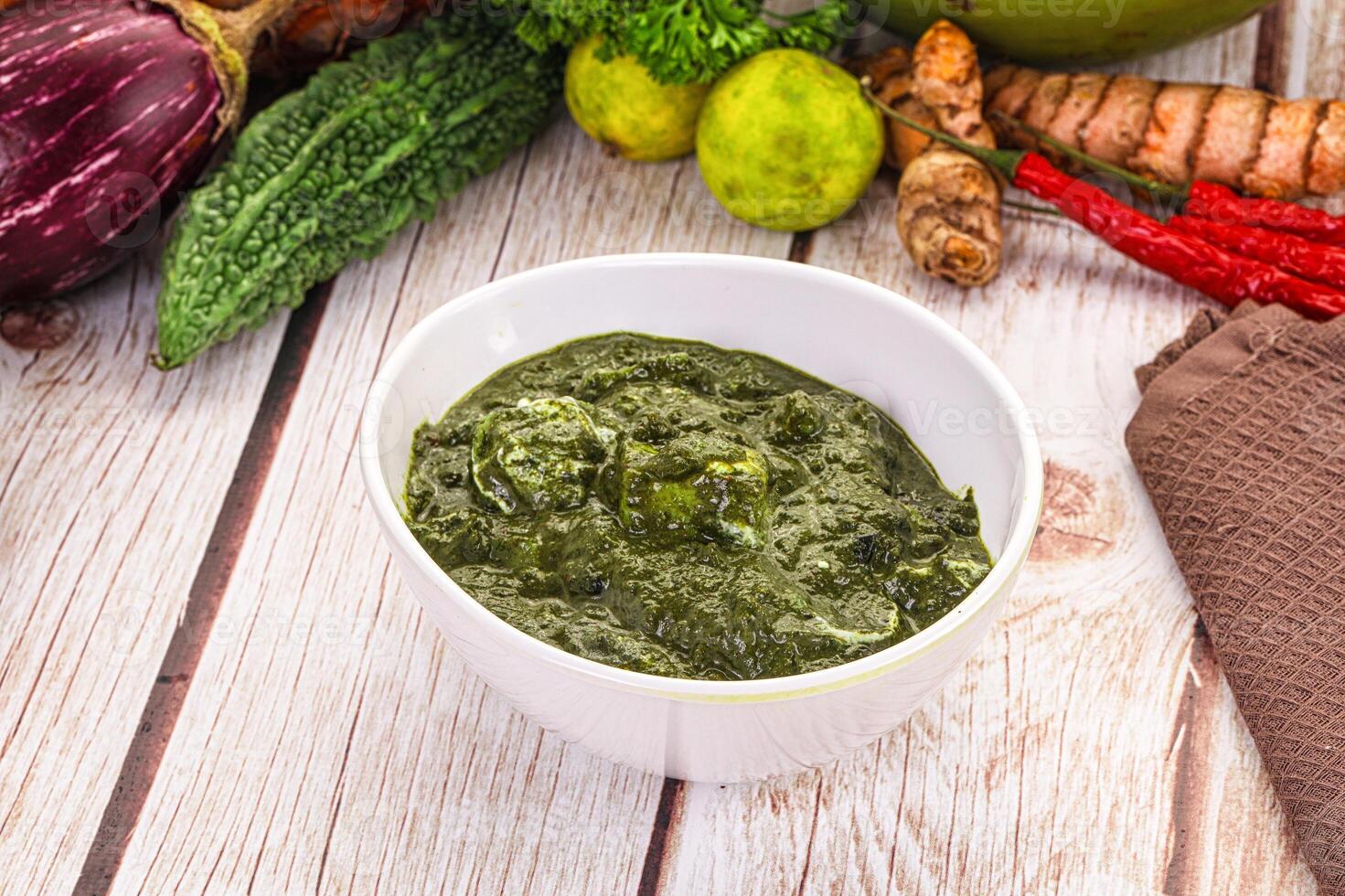 A bowl of green sauce next to a bowl of vegetables photo