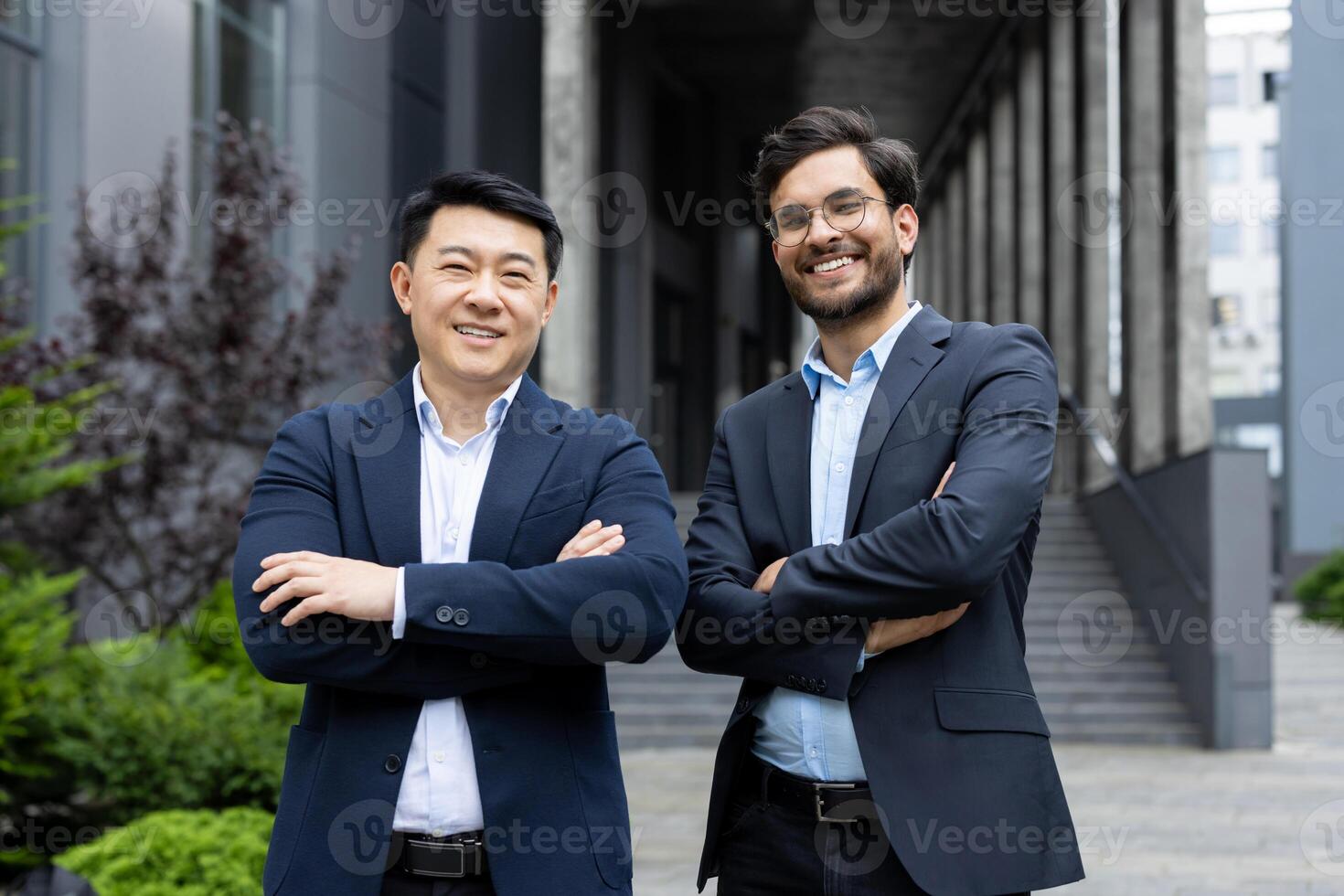 Portrait of two successful businessmen. Colleagues in business suits smiling and looking at camera, men outside office building. photo