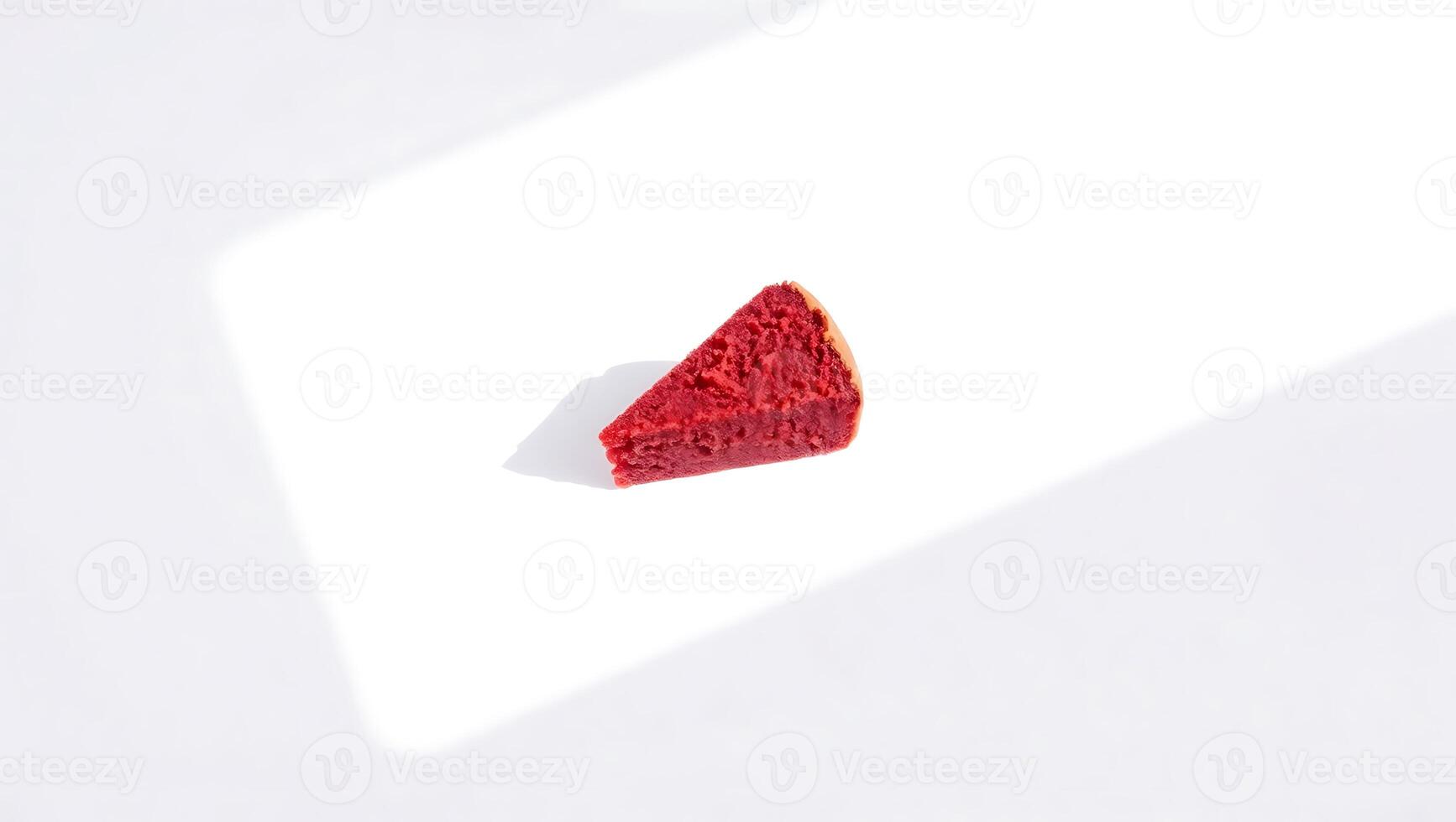 Slice of red velvet cake on a white surface with light shadow photo