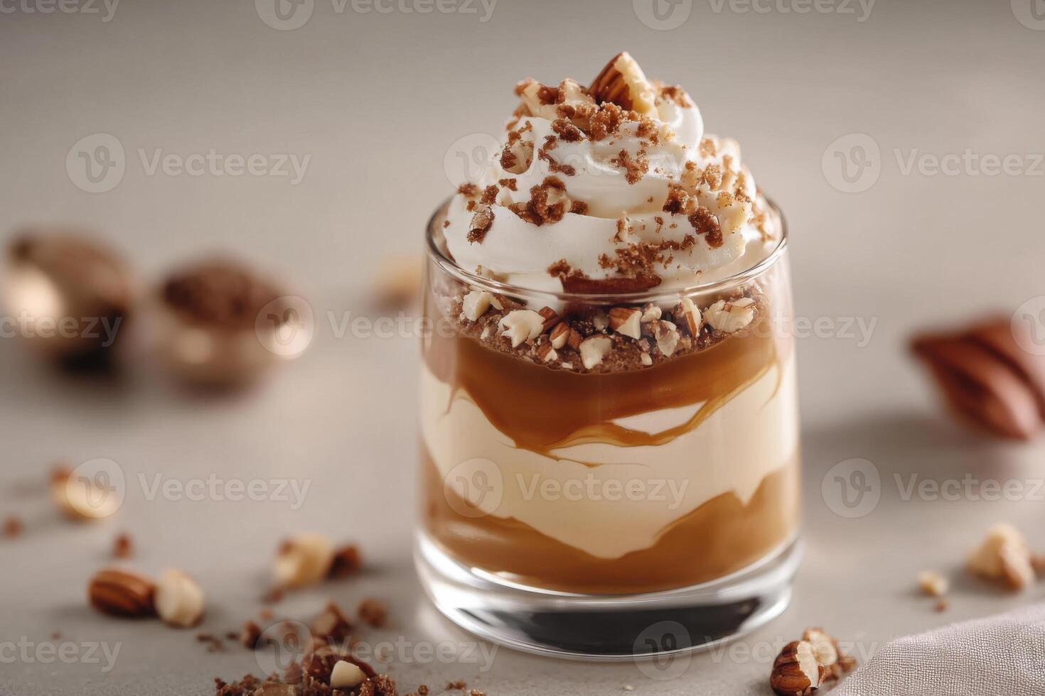 Coffee mousse, topped with a whipped cream, a glossy layer of caramel and a sprinkle of finely chopped nuts, all presented in a sleek art glass. photo