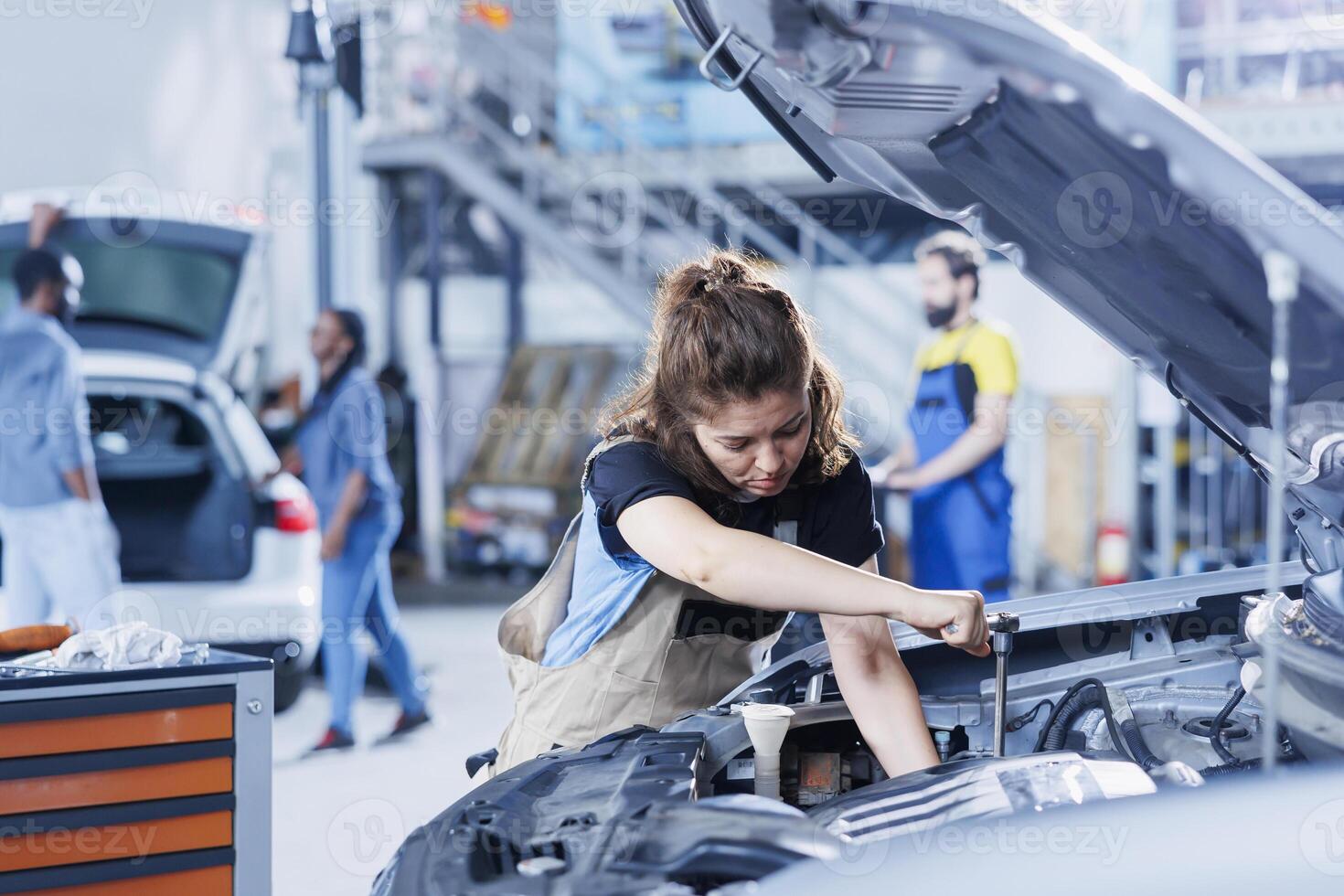Serviceman in car service uses torque wrench to tighten bolts after replacing engine. Competent auto repair shop employee uses professional tools to fix customer automobile photo