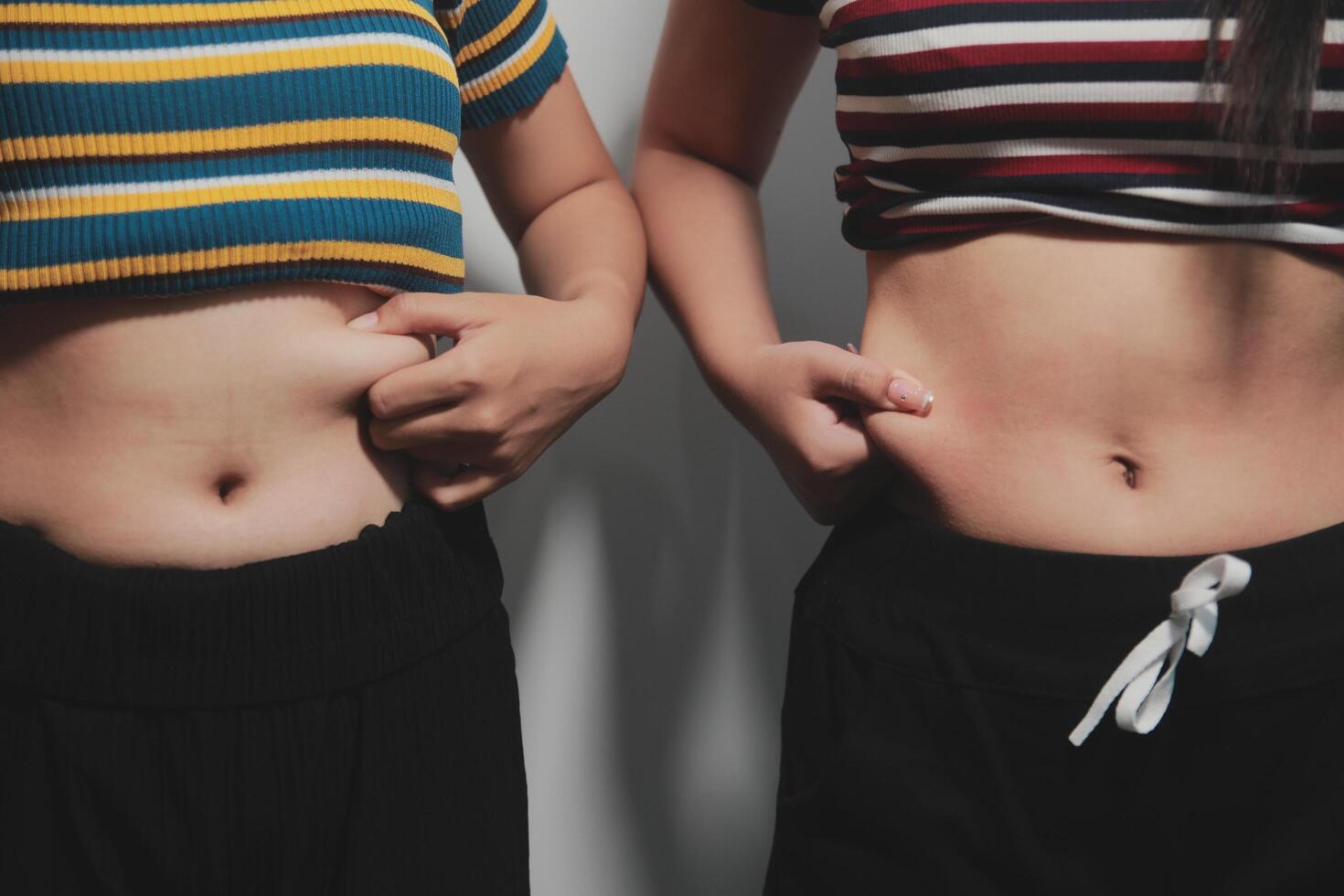 Two women with their stomachs showing photo