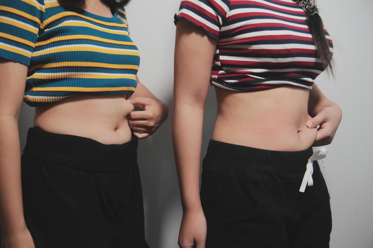 Two women standing next to each other with their stomachs photo