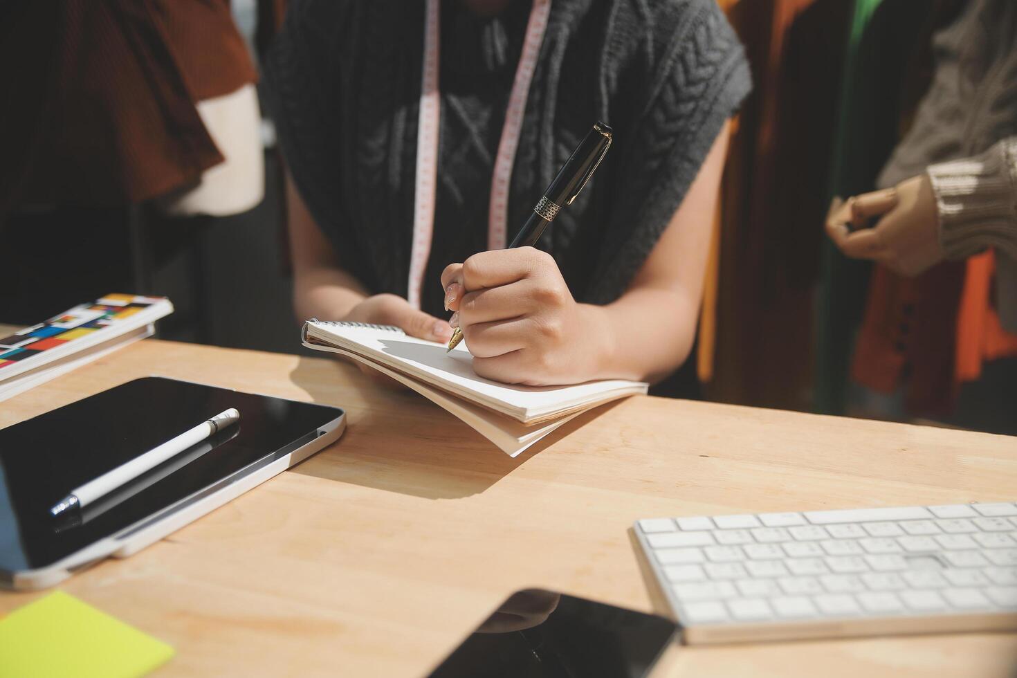 A person is writing in a notebook while sitting at a desk photo