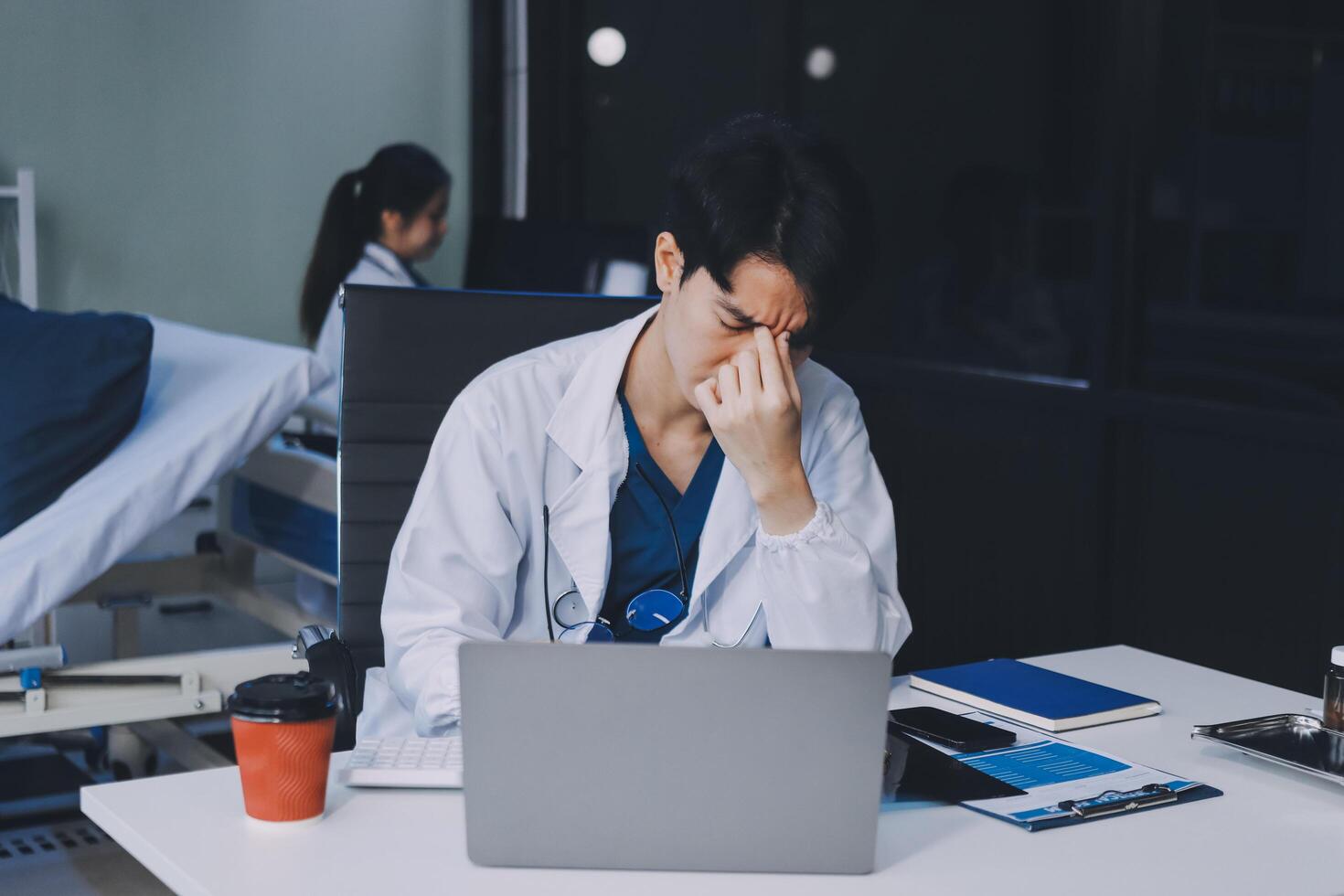 A man in a lab coat sitting at a desk with a laptop photo