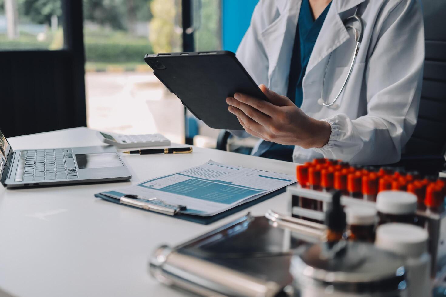 A doctor is using a tablet computer in front of a desk photo