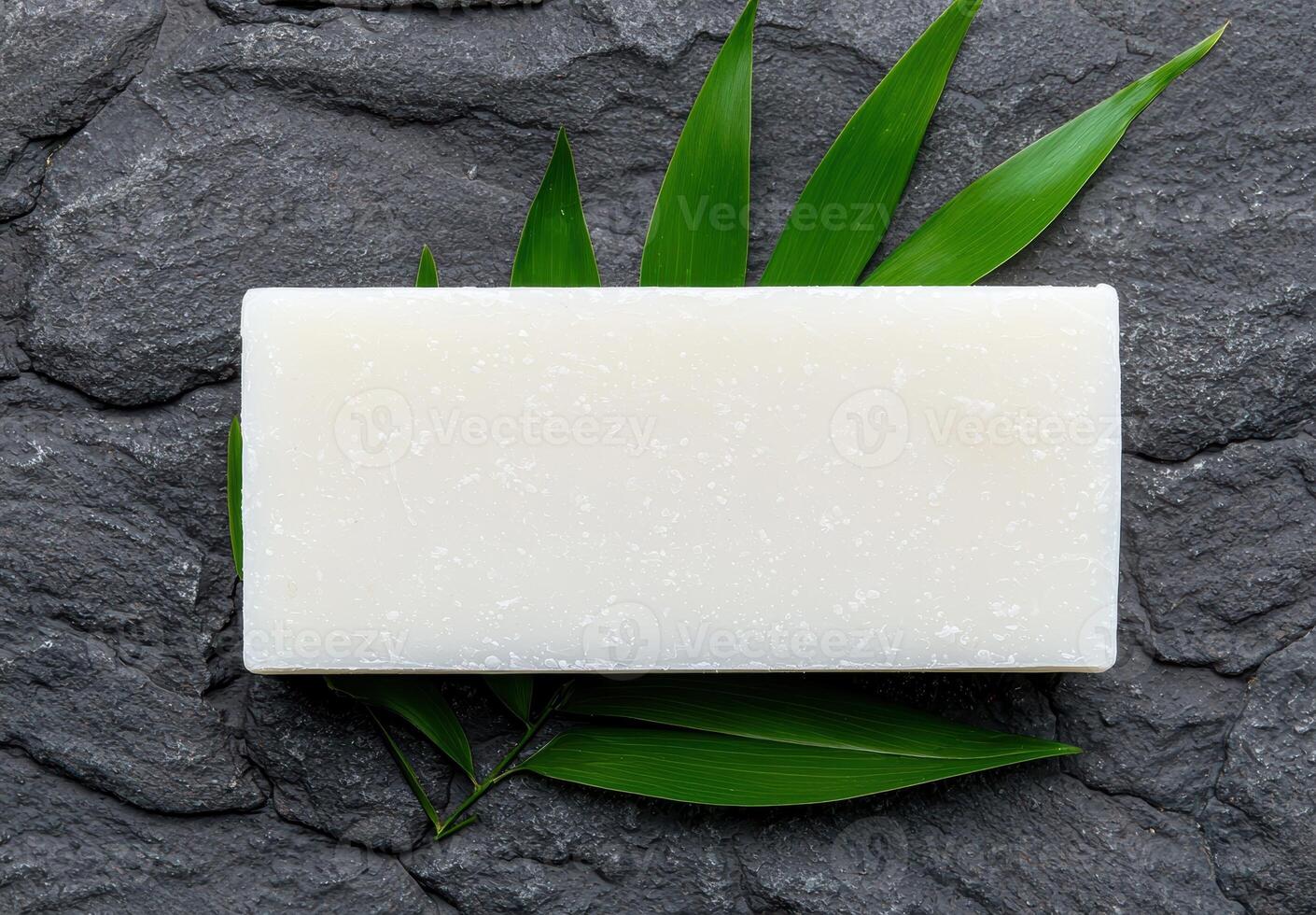 A bar of soap on a slate background with bamboo leaves photo