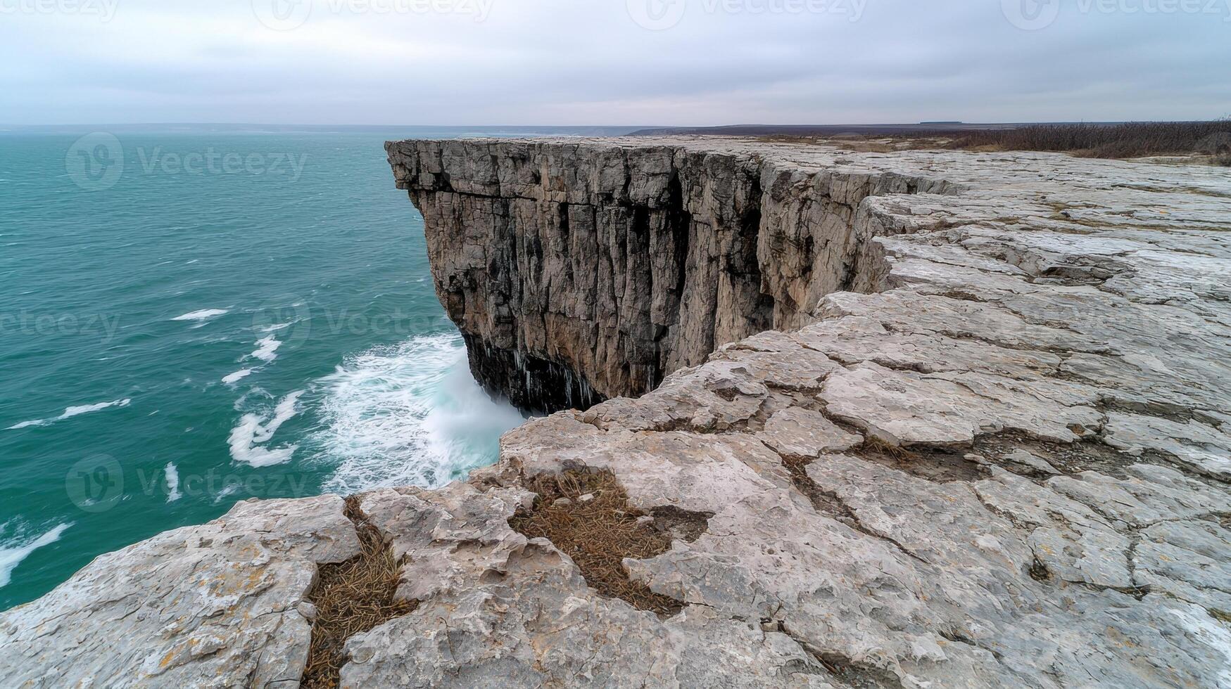 Waves crash against the cliffside on a cloudy day photo