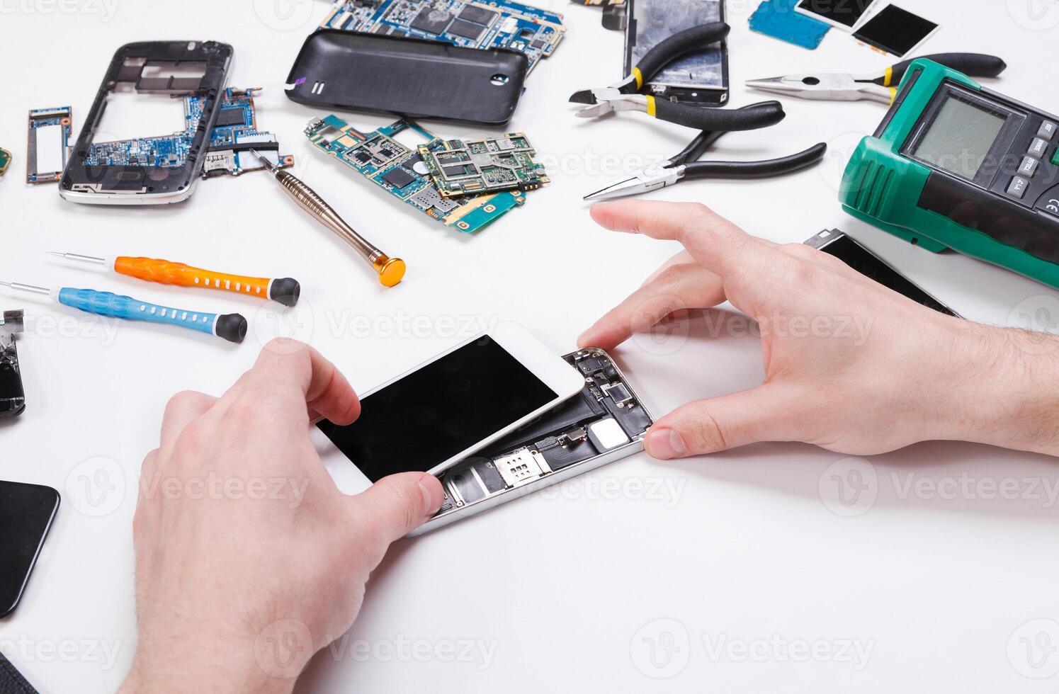 Electronics repair service. Repairman disassembling smartphone for inspecting. Technician fixing broken phone, copy space for text photo