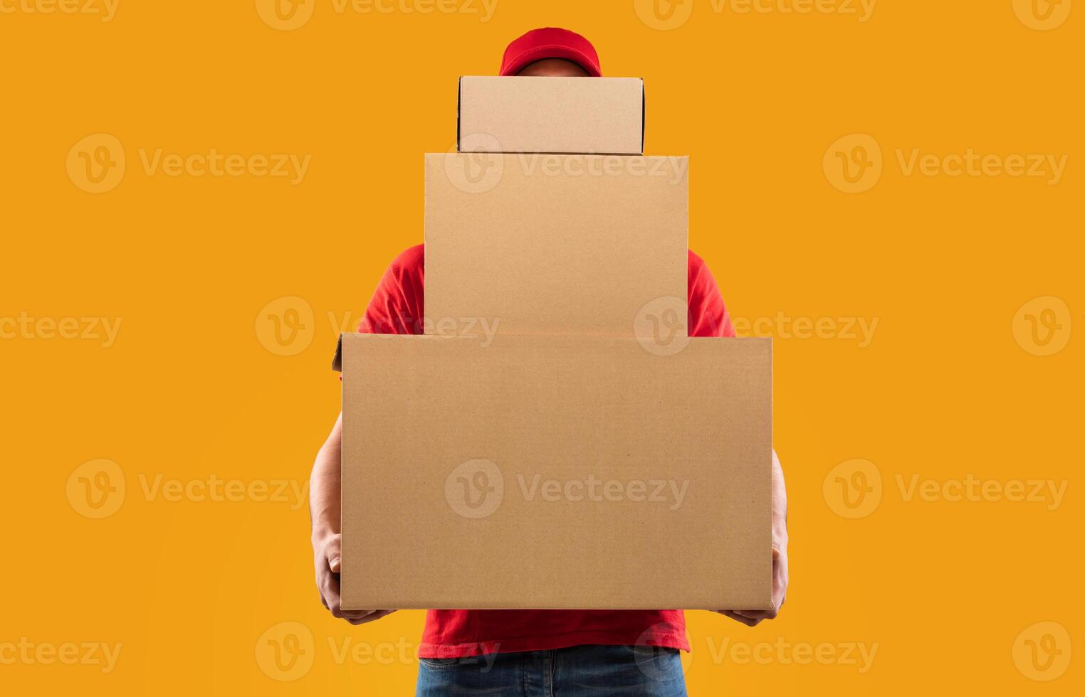 Parcels Delivery. Unrecognizable Courier Guy Holding Many Big Cardboard Boxes Delivering Packages To You Posing Standing In Studio Over Yellow Background. Postal Shipping Service Concept photo
